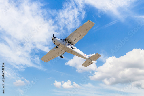 Single engine ultralight plane flying in the blue sky with white clouds