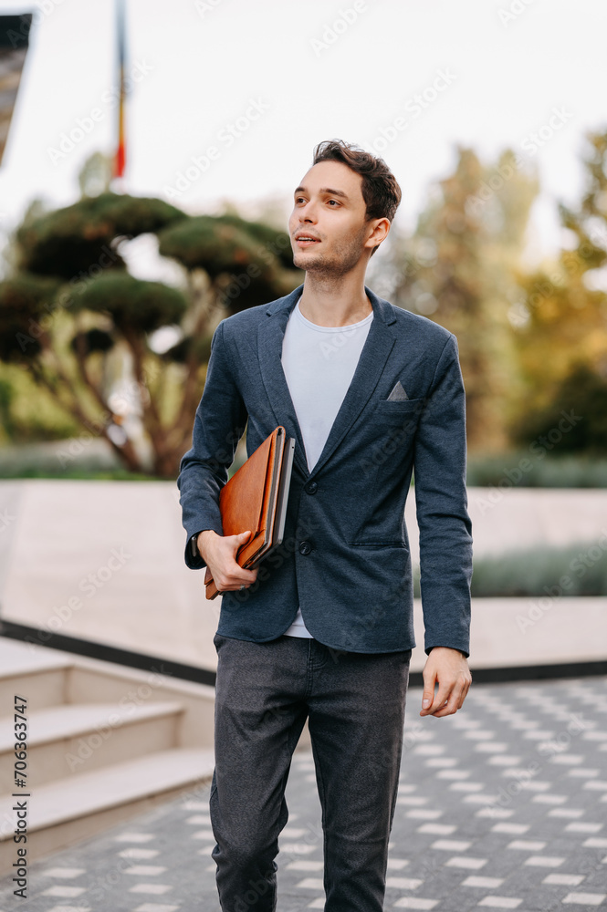 Vertical shot of a young serious man going to his job while holding some papers. Vertical shot of a young serious man going to his job while holding some papers.