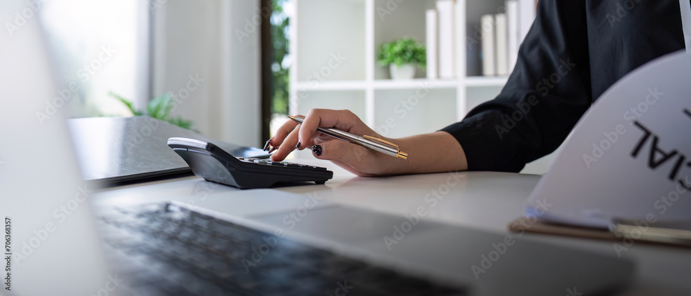 Obraz premium Businesswoman accountant using calculator and laptop for financial data saving in office room, Business financial, tax, accounting concept