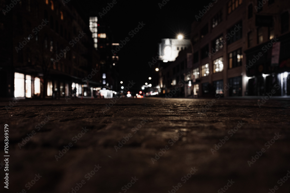 Atmospheric night time shot of an urban street with illuminated signs, buildings, and streetlights
