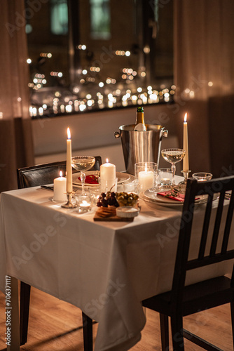 holidays  romantic date and celebration concept - close up of festive table serving for two with champagne bottle in ice bucket and candles burning at home on valentine s day