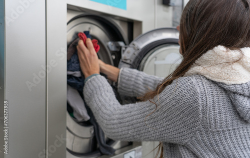 Woman putting clothes into a washing machine at a laundromat