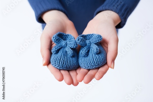 Young beautiful pregnant woman holding baby booties