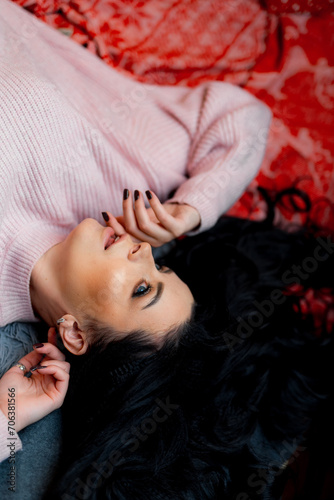 A woman gracefully lays on a bed, surrounded by tranquility, as she dons a cozy pink sweater.