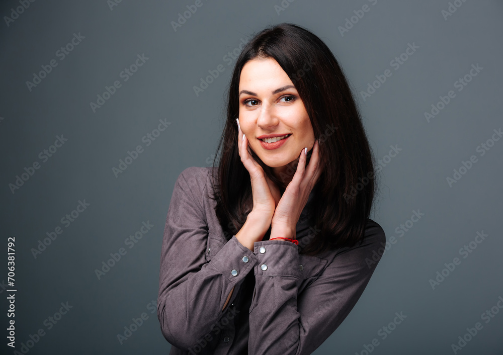 A mesmerizing image capturing the ethereal beauty of a woman as she poses with her hands delicately caressing her face.