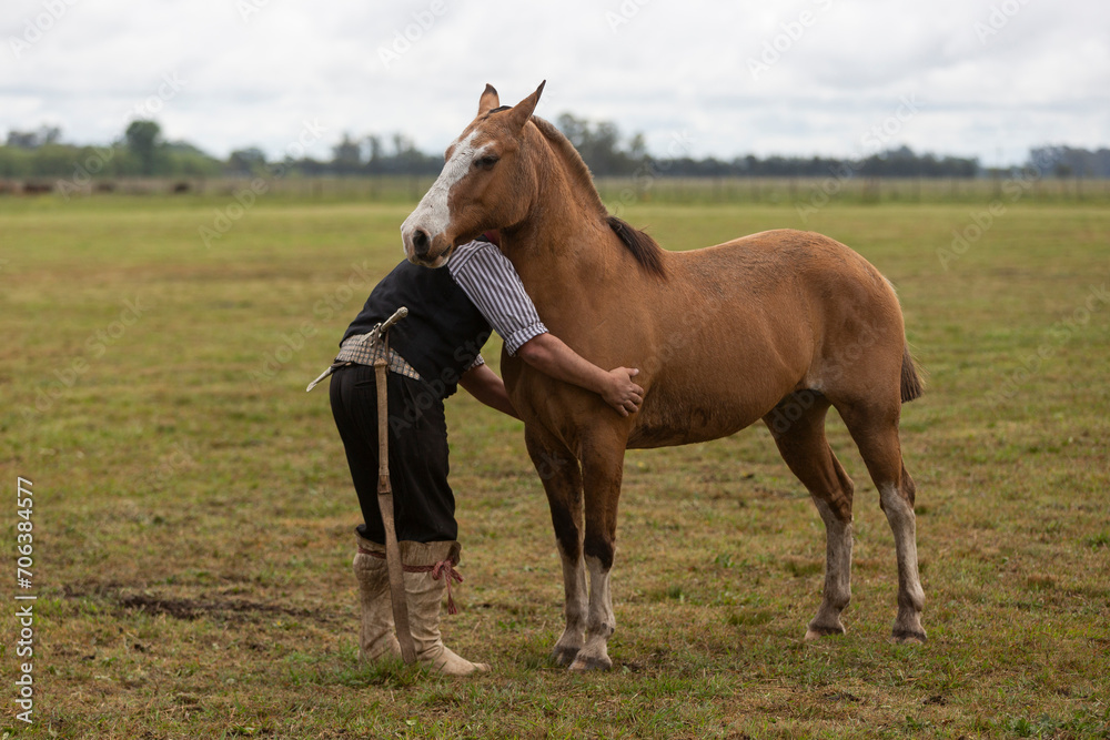 gaucho hugging his horse in the middle of the field