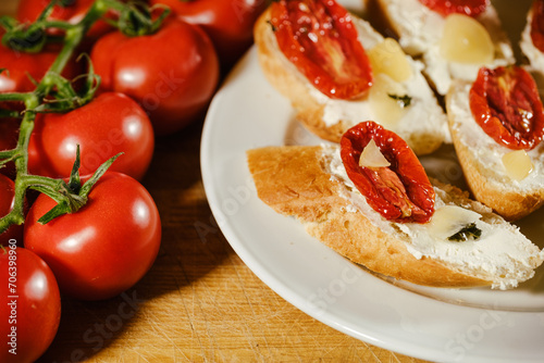 sandwiches with red sun-dried tomatoes and cheese on a plate on the table next to fresh tomatoes