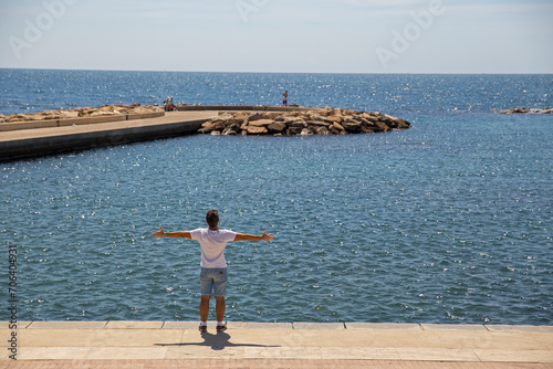 Young boy with raised hands enjoying the summer day by the sea