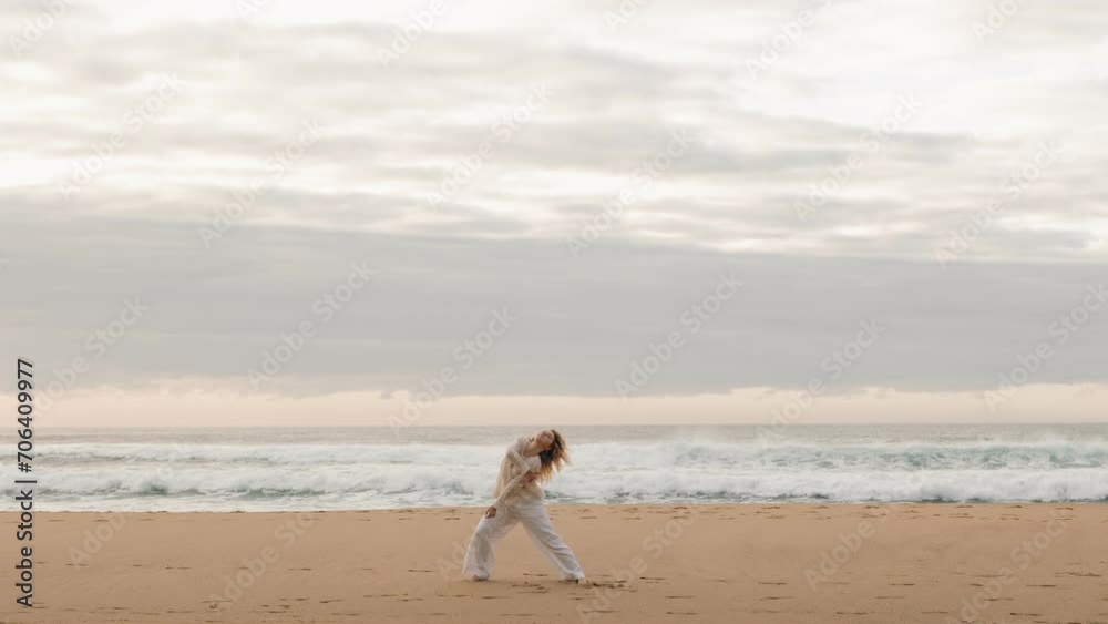 Experience the beauty of artistic dance as a young woman gracefully moves in solitude on an empty beach at sunset. A captivating and serene ocean-side performance. Experience the beauty of artistic dance as a young woman gracefully moves in solitude on an empty beach at sunset. A captivating and serene ocean-side performance.