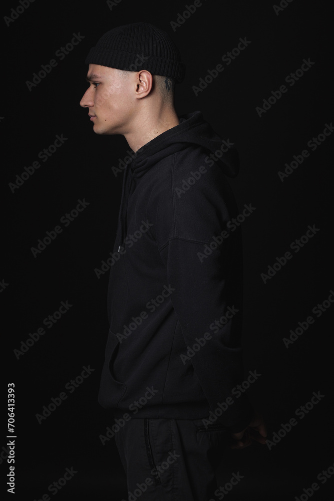 Portrait of a young sad guy in black clothes on a black background. Depressive portrait.