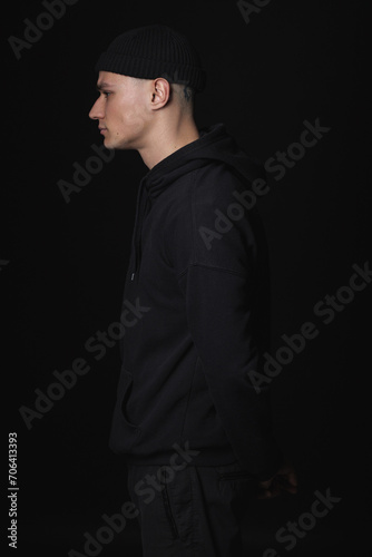 Portrait of a young sad guy in black clothes on a black background. Depressive portrait.