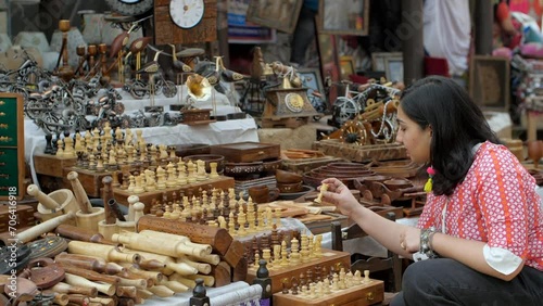 A beautiful Indian woman choosing wooden chess set in the bustling Indian market - Indian fair  Surajkund mela  traditional wooden crafts. A woman doing shoppoing in a street market in India - ches... photo