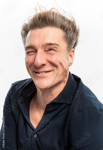 Portrait of elegant European man smiling, wind in his face so strong it deforms his skin. Studio shot photo