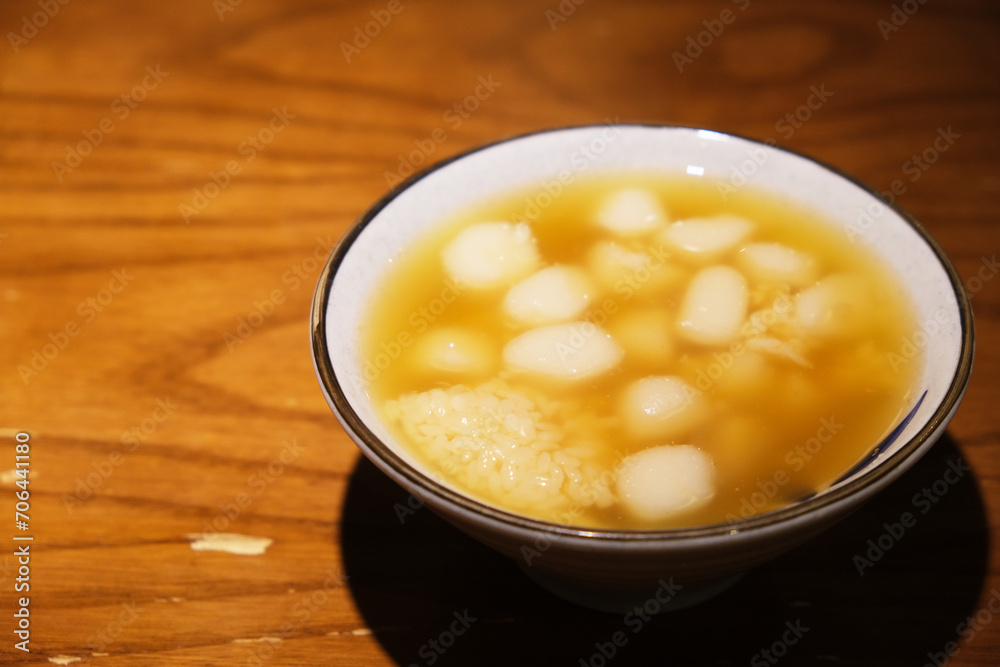 bowl of Glutinous rice balls in sweet rice wine on wooden table. Traditional Chinese dessert. Served during Lantern Festival and Dongzhi Festival in China bowl of Glutinous rice balls in sweet rice wine on wooden table. Traditional Chinese dessert. Served during Lantern Festival and Dongzhi Festival in China