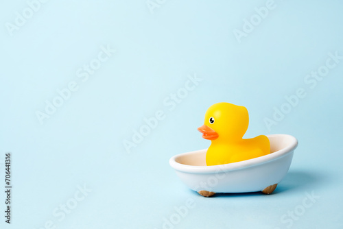 Rubber yellow duck in small bathtub on blue background. Space for copy photo