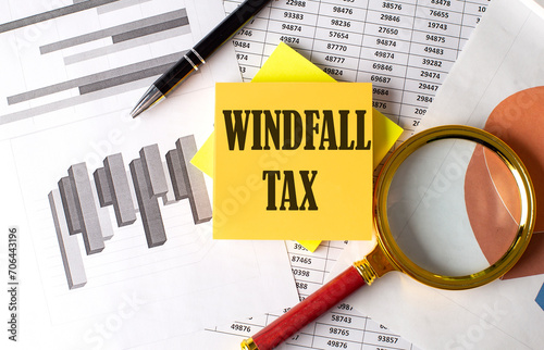 Fotografie WINDFALL TAX text on a sticky on the graph background with pen and magnifier