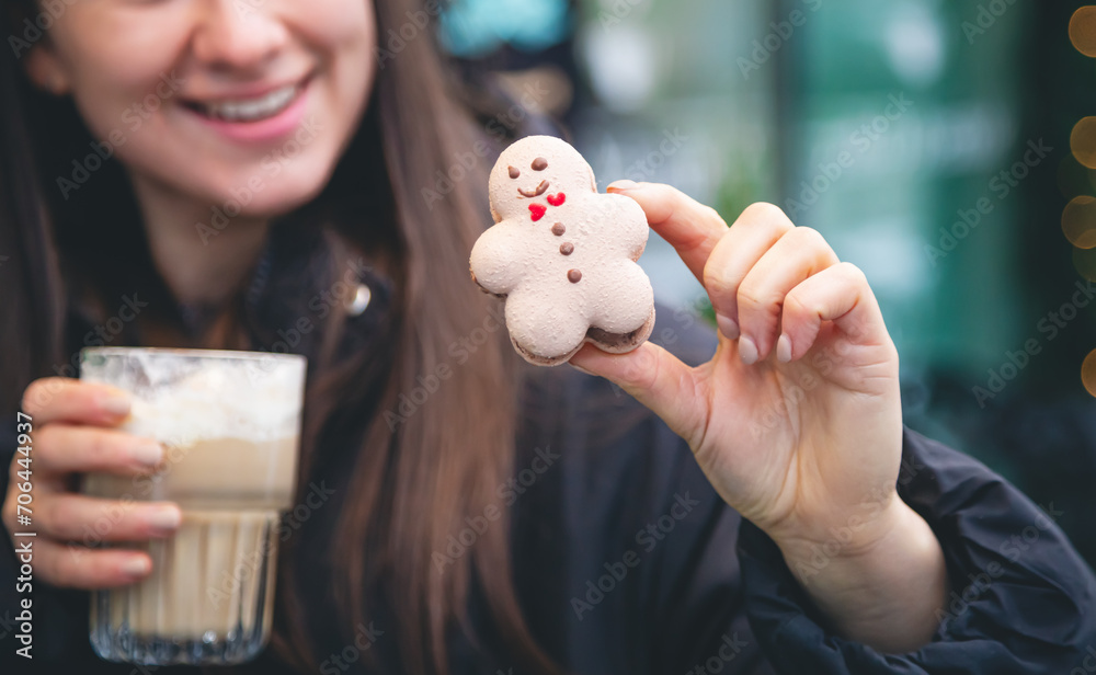 A young woman drinks coffee with a gingerbread boy in a cafe on the street. A young woman drinks coffee with a gingerbread boy in a cafe on the street.