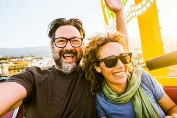 An adult couple of man and woman show expressions and fun during an extreme roller coaster ride. Smiling people have fun at playground during holidays and holidaysOutdoor recreation concept.​