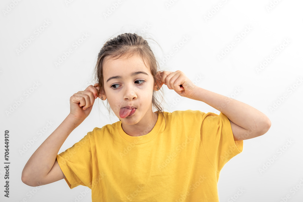 The little girl grimace, holding her ears and sticking out her tongue. The little girl grimace, holding her ears and sticking out her tongue.