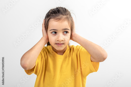 Little Caucasian girl covered her ears on a white background isolated.
