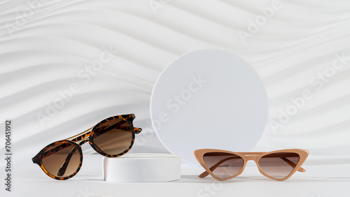 Classic tortoiseshell frame and trendy cat eye frame sunglasses on podiums on white background. Minimal still life. Copy space. Optic store discount, sale, promotion. Sunglasses creative concept.