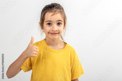 Cheerful little girl showing finger thumb up isolated on white background.