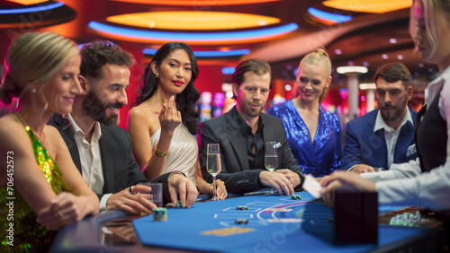 Portrait of a Glamorous Asian Woman at a Blackjack Gambling Table in a Modern Casino. Glamorous Successful Lady Looks at the Camera Calls to Join her at the Table, Smiling while People Win. photo