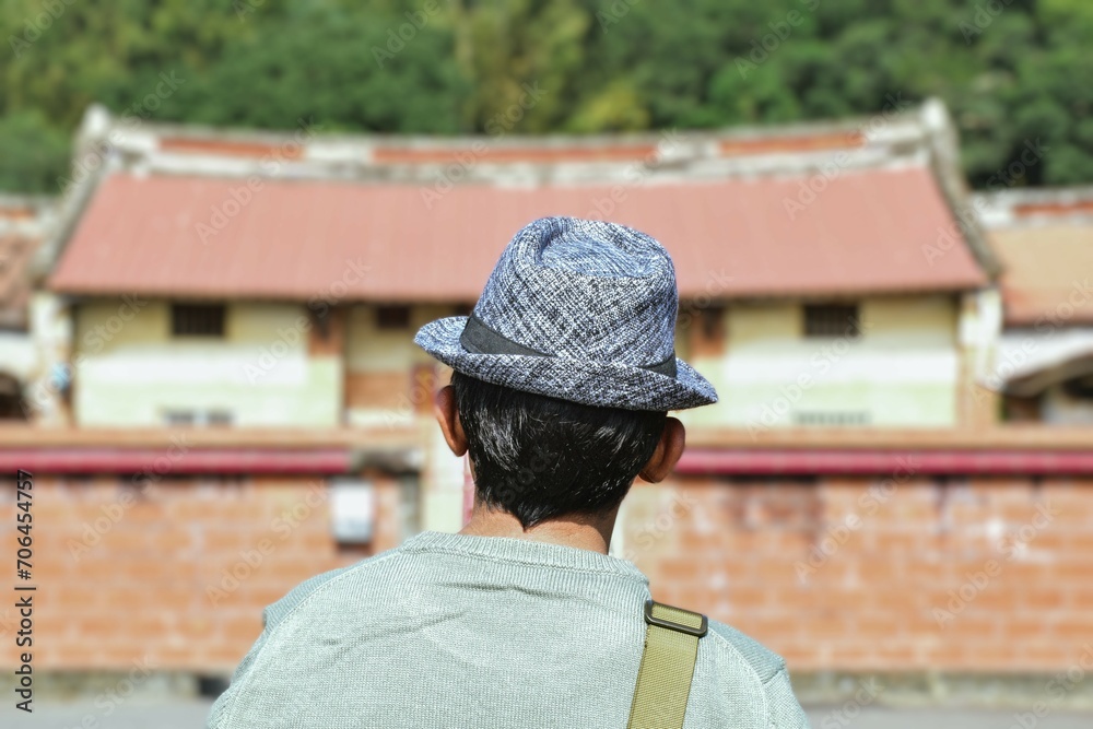 Tourist with hat infront of a traditional Chinese old house. Selective focus. Solo travelling Asia concept.