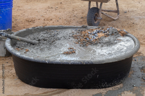 Black plastic bucket and hoe for mixer wet cement in construction site for background.