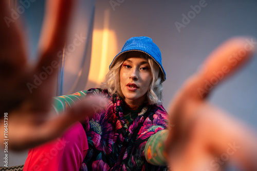 Cool hipster student woman wearing stylish outfit looking at camera and correcting her hat