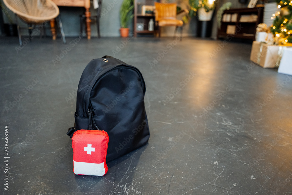 Obraz premium A travel first aid kit, a minimum set of medicines for the trip, a black backpack on the floor, a travel bag, a mini first aid kit.