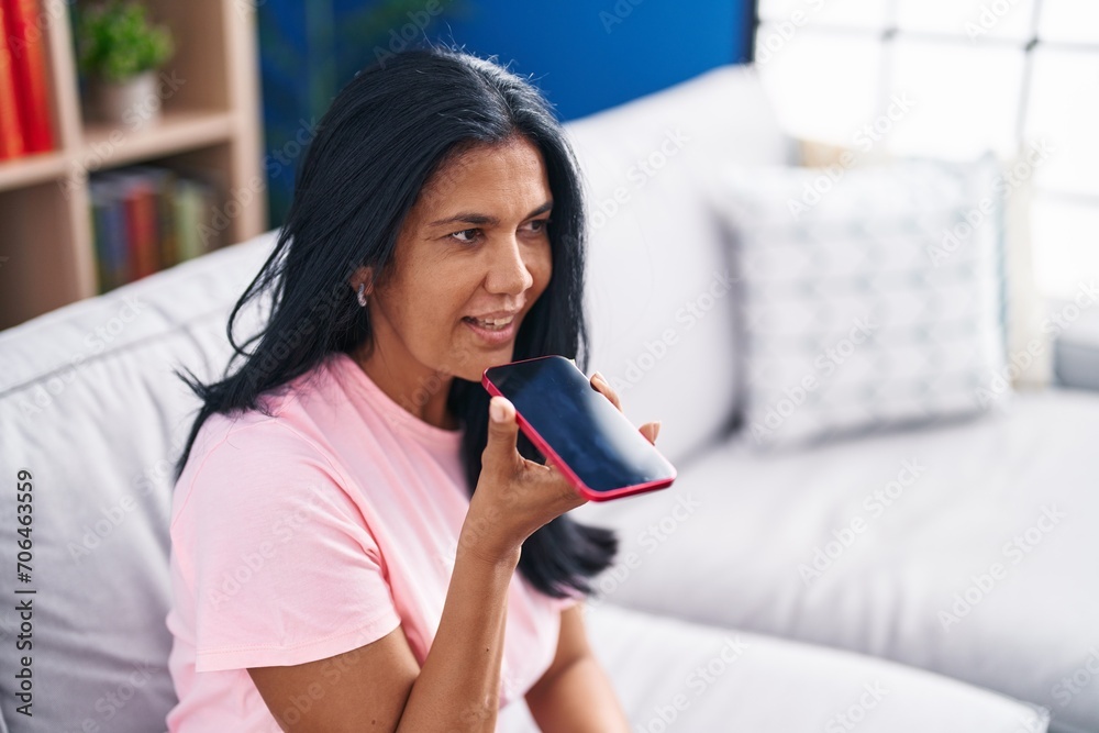 Middle age hispanic woman talking on the smartphone sitting on sofa at home Middle age hispanic woman talking on the smartphone sitting on sofa at home