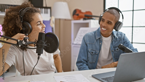 Working musicians donning headphones together at radio studio table, live on air, presenting music and news with smiles, professionalism, on a casual day. photo