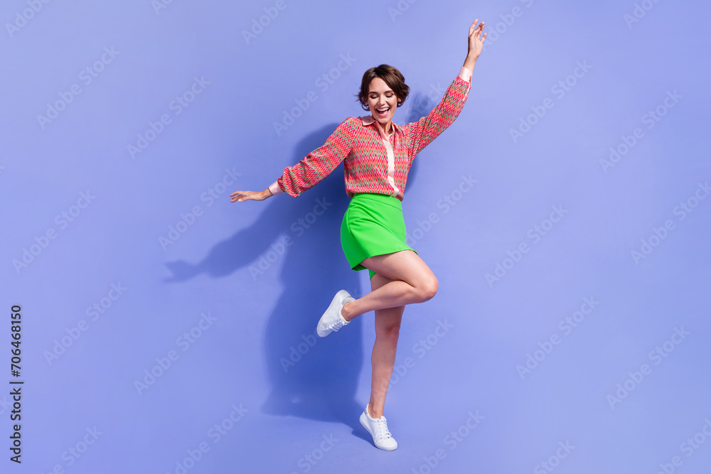 Full length photo of good mood gorgeous funny girl wear stylish shirt green skirt dancing having fun isolated on blue color background Full length photo of good mood gorgeous funny girl wear stylish shirt green skirt dancing having fun isolated on blue color background