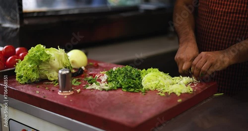 Turkish man cuts fresh cabbage and lettuce in the kitchen - Traditional coban salad photo