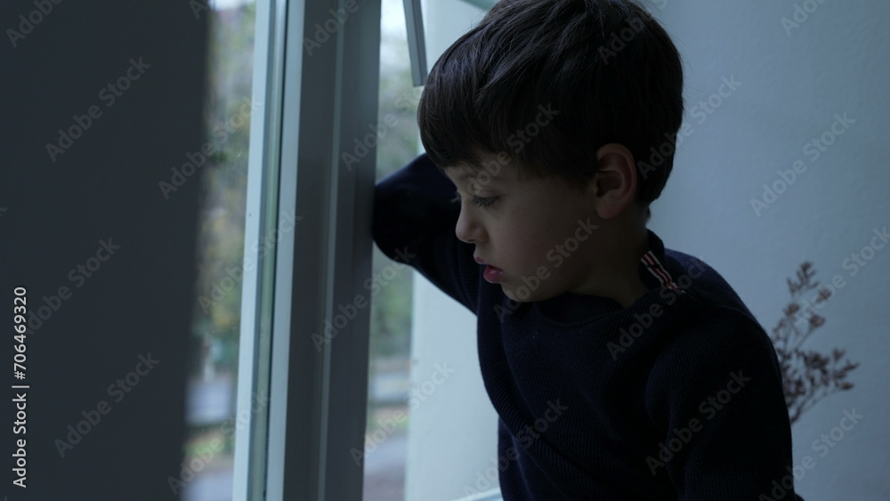 Bored child stuck at home with nothing to do, little boy leaning on glass window feeling boredom Bored child stuck at home with nothing to do, little boy leaning on glass window feeling boredom
