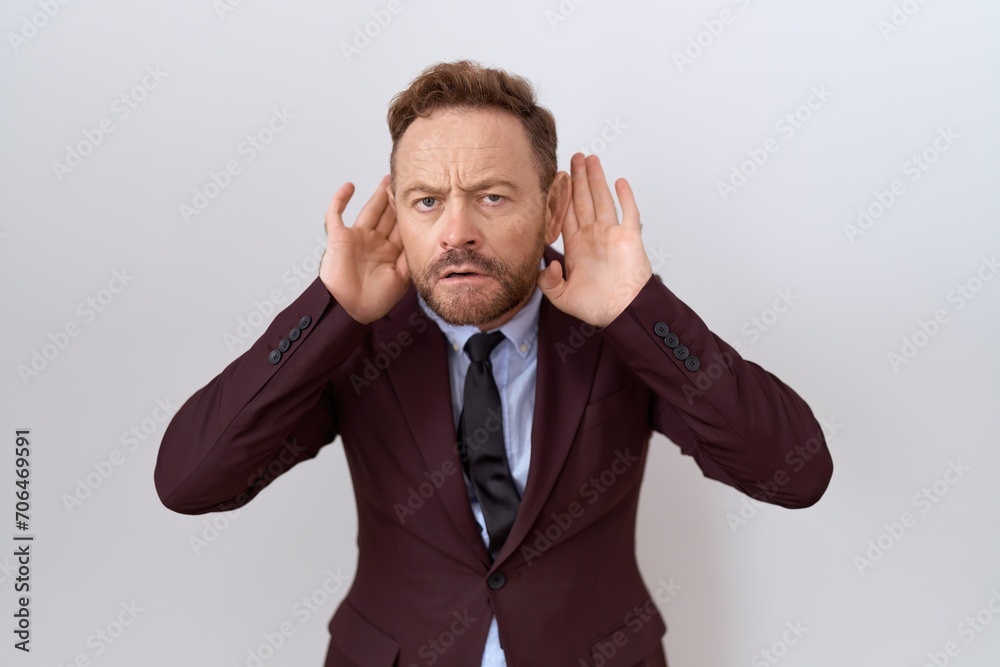 Middle age business man with beard wearing suit and tie trying to hear both hands on ear gesture, curious for gossip. hearing problem, deaf Middle age business man with beard wearing suit and tie trying to hear both hands on ear gesture, curious for gossip. hearing problem, deaf