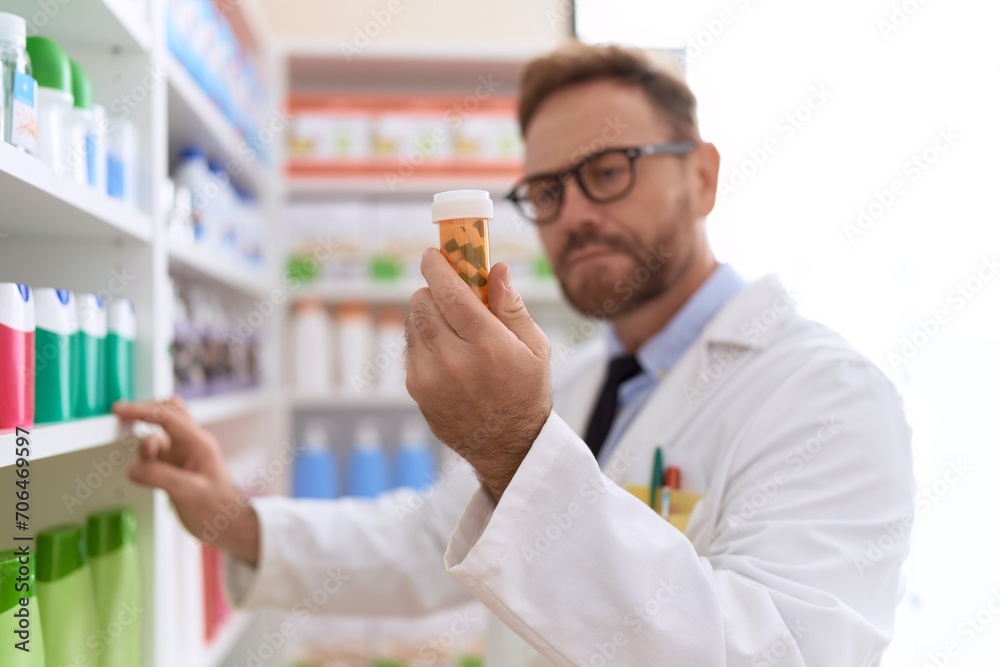 Middle age man pharmacist reading pills bottle label at pharmacy Middle age man pharmacist reading pills bottle label at pharmacy