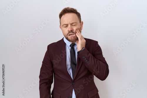 Middle age business man with beard wearing suit and tie touching mouth with hand with painful expression because of toothache or dental illness on teeth. dentist