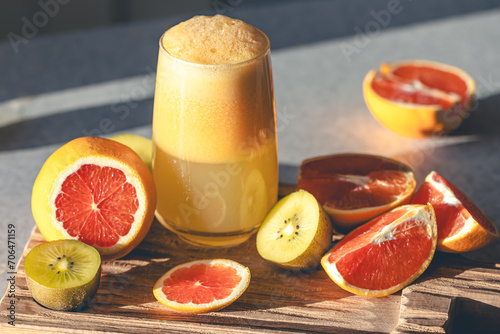 Fototapeta Naklejka Na Ścianę i Meble -  A glass of freshly squeezed juice and fruits on a wooden cutting board.