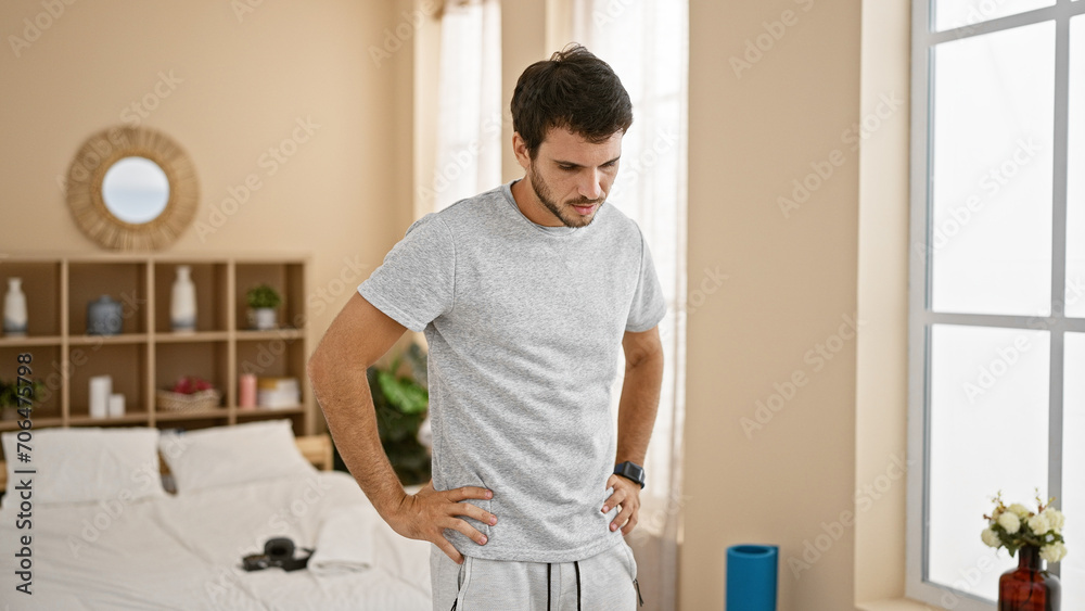 Handsome young hispanic man standing pensively in a cozy bedroom interior, embodying casual home life. Handsome young hispanic man standing pensively in a cozy bedroom interior, embodying casual home life.