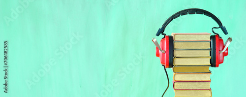 Relaxing with audiobooks concept with heap of books and vintage headphones.Bright green background with large copy space