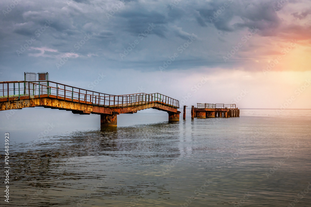 Old ruined pier in the sea under stormy clouds