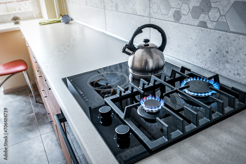 Steel kettle with whistle on modern burning gas stove photo