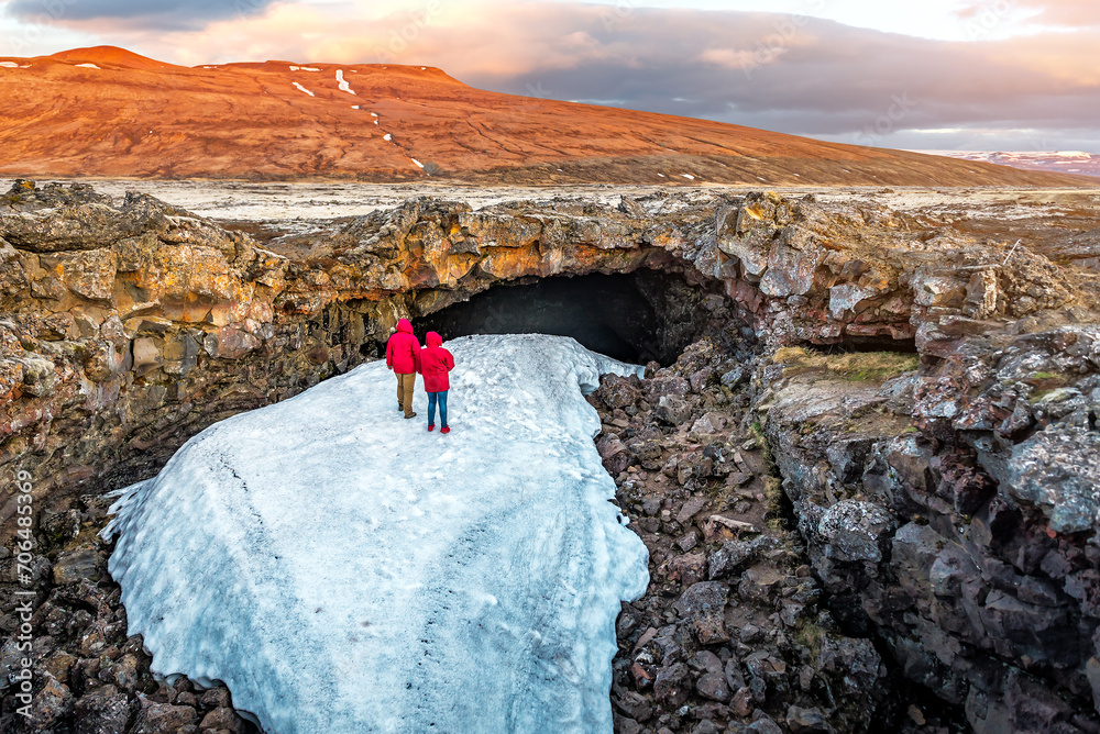Two tourists in red watching Surthellir lava Caves in Iceland