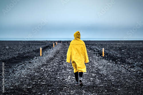 Woman in yellow walks through a wild desert road in Iceland. Wilderness in Iceland photo