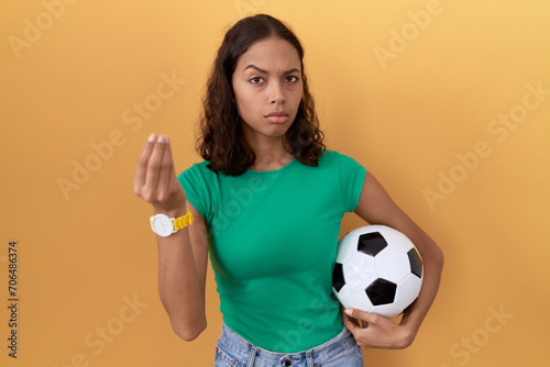 Young hispanic woman holding ball doing italian gesture with hand and fingers confident expression © Krakenimages.com