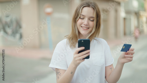 Young caucasian woman using smartphone and credit card at street