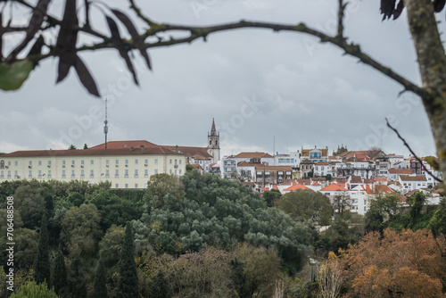 Viewpoint with blurred branch framing to hill and Santarém architecture and tower of Santa Maria de Marvila Church, PORTUGAL