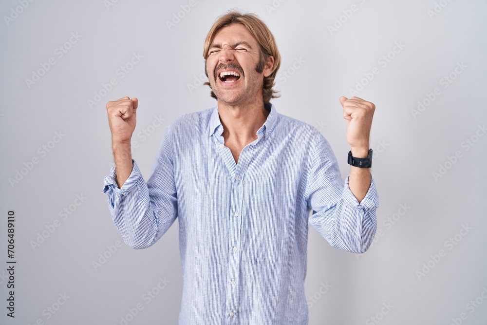 Caucasian man with mustache standing over white background celebrating surprised and amazed for success with arms raised and eyes closed. winner concept. Caucasian man with mustache standing over white background celebrating surprised and amazed for success with arms raised and eyes closed. winner concept.